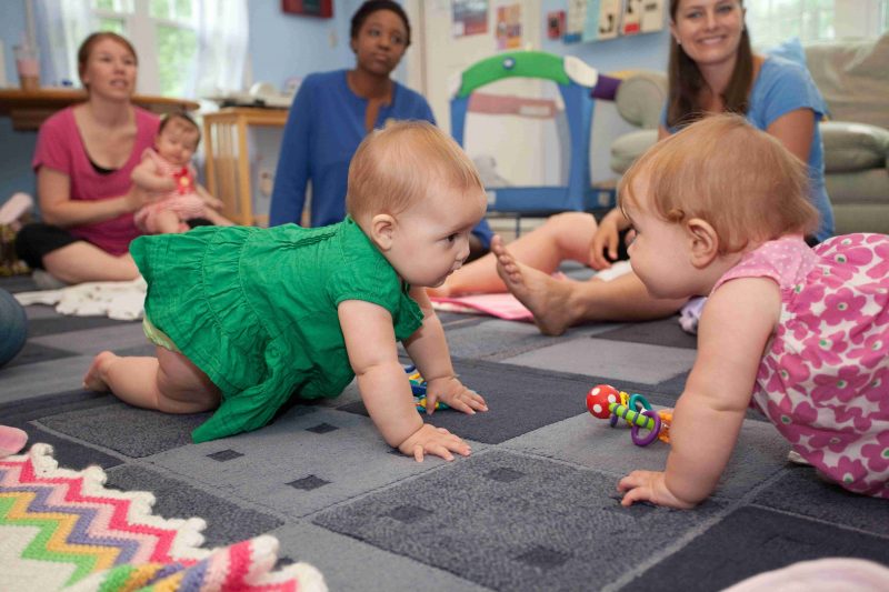 Babies crawling on the floor with moms watching
