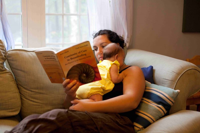 Mom reading a book holding a baby